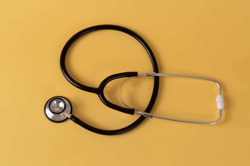 Close-up of a black stethoscope on a vibrant yellow surface, ideal for medical themes.
